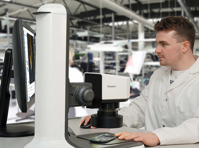 DeepFocus1_bench_stand_ring_light_mobile_phone_inspection_768x572px Man in factory using DeepFocus1 microscope